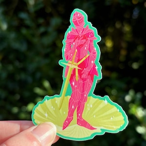 Op de afbeelding: Een sticker met een roze ridder in harnas, met een geel zwaard. De ridder staat op een geel en groene waaiervormige basis met glinsterende accenten. De sticker heeft een groene rand en een vage groene achtergrond.