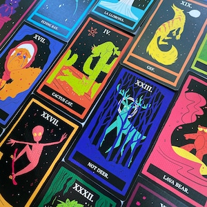 May include: A set of colorful playing cards with illustrations of various creatures and characters. The cards feature black backgrounds with white text and colorful illustrations. The cards include titles such as "Flying Ray", "Cactus Cat", "Not Deer", "Lava Bear", and "Gef."