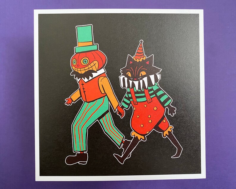 May include: A black cat wearing a red and green jester costume with a white collar and teeth, and a pumpkin wearing a green hat and a red and green striped shirt, on a black background.