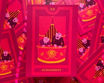 May include: A tarot card with a red and pink color scheme. The card features two men in a theater box, with the word "JUDGEMENT" at the bottom. The card is surrounded by other cards with the same design.