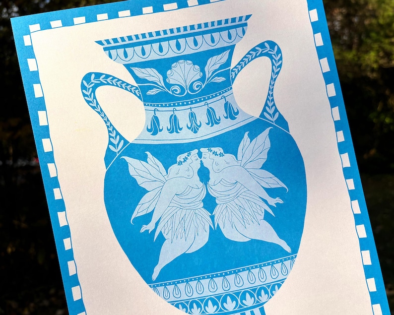 May include: A blue and white print featuring a classical vase design. The vase is adorned with floral and geometric patterns, and depicts two winged figures kissing. The print has a white border with blue square accents.