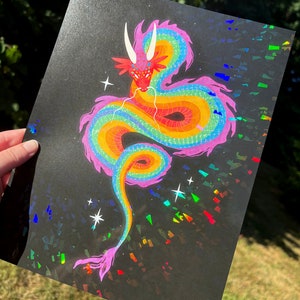 May include: A rainbow colored dragon with a pink body and yellow, orange, green, and blue scales. The dragon is curled up in a circle with its head facing the viewer. The background is black with iridescent glitter.