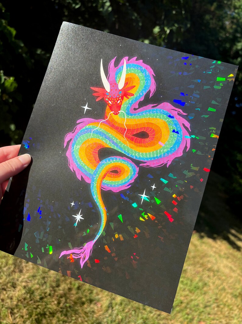 May include: A rainbow colored dragon with a pink body and yellow, orange, green, and blue scales. The dragon is curled up in a circle with its head facing the viewer. The background is black with iridescent glitter.