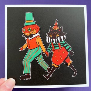 May include: A black and white illustration of a pumpkin-headed character and a black cat wearing a jester's hat. The pumpkin character is wearing a striped shirt and trousers, while the cat is wearing a striped shirt and red overalls. Both characters are smiling.