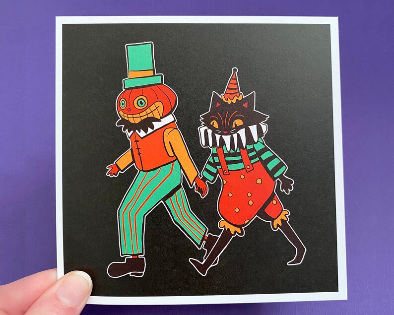 May include: A black and white illustration of a pumpkin-headed character and a black cat wearing a jester's hat. The pumpkin character is wearing a striped shirt and trousers, while the cat is wearing a striped shirt and red overalls. Both characters are smiling.