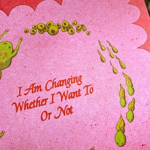 May include: A pink card with a scalloped edge features a whimsical illustration of frogs and tadpoles. The text "I Am Changing Whether I Want Or Not" is written in red script. The frogs are green with orange spots.