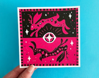 Puede incluir: Una impresión artística cuadrada con un diseño negro y rosa intenso. Presenta dos conejos negros estilizados con cuernos y patrones de estrellas, sobre un fondo negro y rosa intenso. Un diseño de ojo blanco con líneas radiales está en el centro.