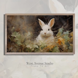 May include: A white rabbit with pink ears sits in a bed of green and brown leaves. The rabbit is looking directly at the viewer. The background is a dark brown.