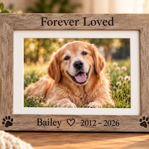 May include: A rectangular wooden picture frame with a light brown wood grain finish. The top border is engraved with the text "Forever Loved" and the bottom border features two paw prints, the name "Bailey", a heart, and "2012 - 2026".