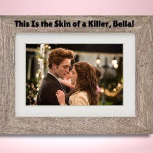 May include: A framed photograph of a couple dancing at a formal event. The man is wearing a black suit and the woman is wearing a white dress. The text "This Is the Skin of a Killer, Bella!" is printed at the top of the frame.