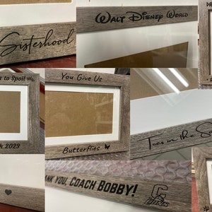 May include: A collection of rustic wooden picture frames with various engraved sayings, including "The Sisterhood", "Another Princess to Spoil", "You Give Us Butterflies", "Daddy's Little Bonobo", "Axel Thorvald", "Toes in the Sand", "Oscar", "Yalya", "Thank You, Coach Bobby!" and "Fuzz".