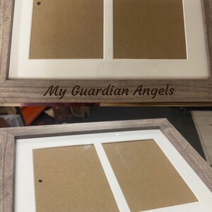 May include: A wooden picture frame with two openings for photos. The frame has a white mat and a brown wood finish. The frame is engraved with the text "My Guardian Angels".
