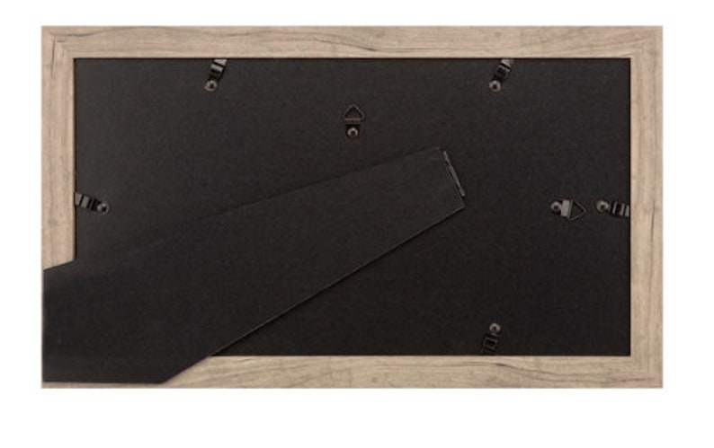 May include: A light brown wood picture frame with a black mat and a sawtooth hanger on the back.
