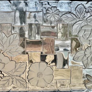 May include: A decorative glass panel with a woven basket pattern and embossed floral and leaf designs. The flowers and leaves are in a lighter tone, creating a contrast with the background.