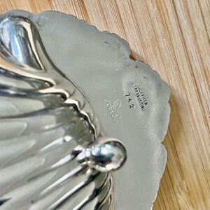 May include: Silver shell-shaped dish with a handle. The bottom of the dish is marked "Sheffield England" and "742".