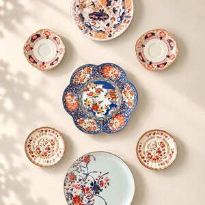 Pu&ograve; includere: Un set di sette piatti e piattini in ceramica con vari motivi floreali nei colori blu, arancione, rosso e bianco. Il set comprende un grande piatto smerlato, un piatto rotondo con base azzurra e diversi piattini pi&ugrave; piccoli abbinati.