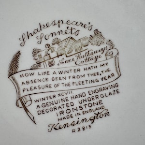 May include: A brown and white ceramic plate with a Shakespeare's Sonnets design. The design features a cottage with the text "Anne Hathaway's Cottage" and a quote from Shakespeare's Sonnet 97: "How like a winter hath my absence been from thee, the pleasure of the fleeting year." The plate is marked "Winter XCVII, A genuine hand engraving decorated underglaze Ironstone, Made in England, Kensington, R2815."