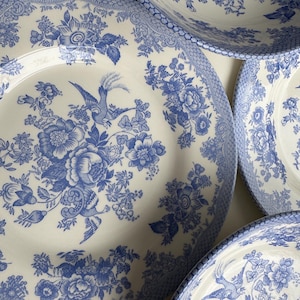 K&ouml;nnte beinhalten: Ein Satz von vier blauen und wei&szlig;en Keramiktellern mit einem Blumenmuster und einem Vogeldesign. Die Teller sind alle unterschiedlich gro&szlig; und werden &uuml;bereinander gestapelt.