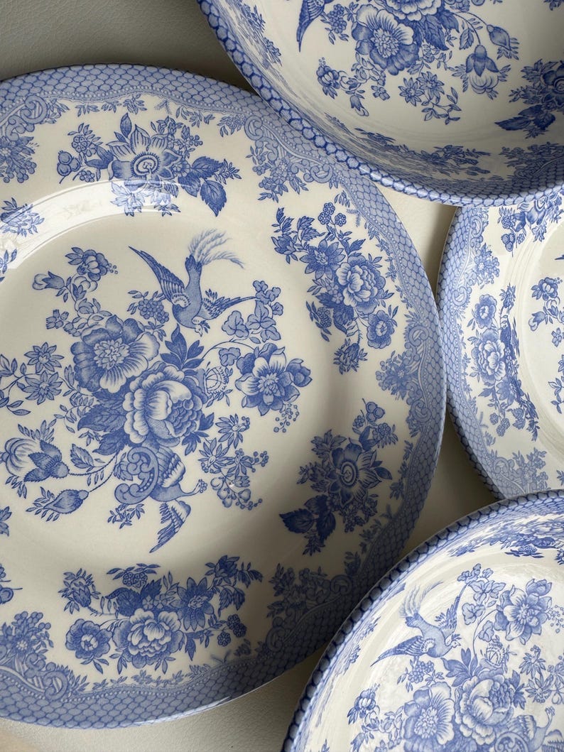 K&ouml;nnte beinhalten: Ein Satz von vier blauen und wei&szlig;en Keramiktellern mit einem Blumenmuster und einem Vogeldesign. Die Teller sind alle unterschiedlich gro&szlig; und werden &uuml;bereinander gestapelt.