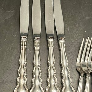 K&ouml;nnte beinhalten: Vier silberne Essmesser mit verzierten Griffen. Die Messer haben eine polierte Oberfl&auml;che und sind nebeneinander angeordnet.