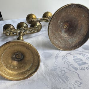 Pu&ograve; includere: Diversi candelabri antichi in ottone. I candelabri hanno una base rotonda e una parte superiore decorativa con pi&ugrave; bracci per candele. L'ottone ha un aspetto ossidato e invecchiato, suggerendo che si tratta di pezzi d'epoca.