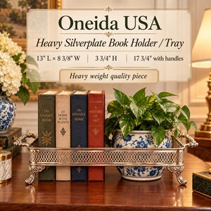 May include: A rectangular silverplate tray with an ornate lattice-patterned side and four decorative feet. The tray holds four books titled The Garden Book, At Home With Plants, The Kinfolk Home, and A History Of Art, plus a blue and white floral planter.