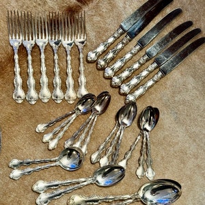 May include: A set of silverware with ornate handles. The set includes forks, knives, and spoons, all made of polished silver.