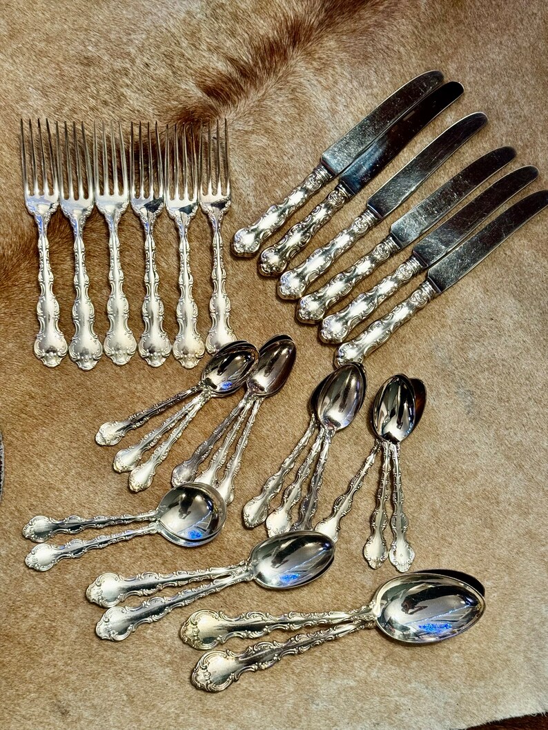 May include: A set of silverware with ornate handles. The set includes forks, knives, and spoons, all made of polished silver.