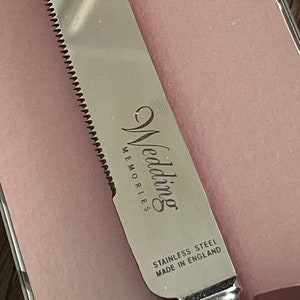 May include: Silver cake knife with a serrated edge and the words "Wedding Memories" and "Stainless Steel Made in England" engraved on the blade.