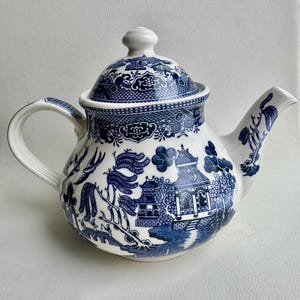 K&ouml;nnte beinhalten: Eine blaue und wei&szlig;e Teekanne mit einem Weidenmuster. Die Teekanne hat einen runden K&ouml;rper und einen Deckel mit einem Knopf oben.