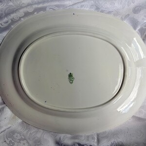 May include: An oval white ceramic serving platter with a smooth, glossy finish. The underside features a centered green maker's mark with the text Royal Grafton Bone China, indicating the brand and material of this vintage kitchenware piece.