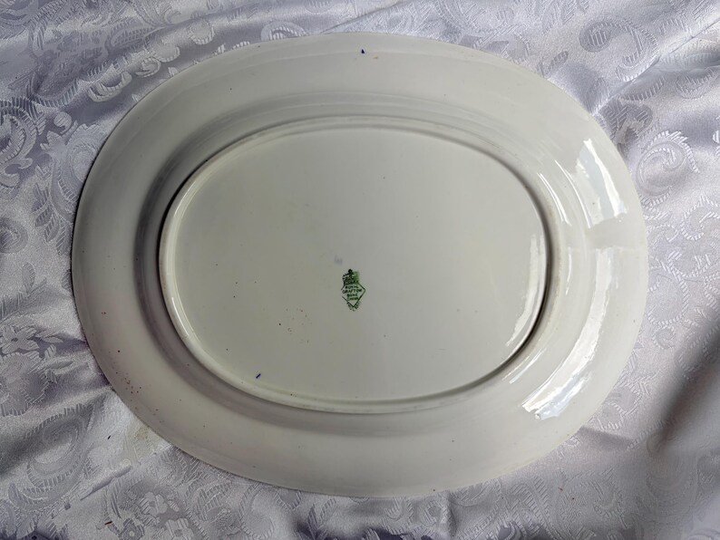 May include: An oval white ceramic serving platter with a smooth, glossy finish. The underside features a centered green maker's mark with the text Royal Grafton Bone China, indicating the brand and material of this vintage kitchenware piece.