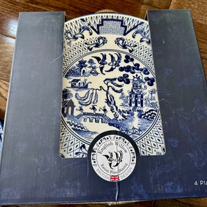 K&ouml;nnte beinhalten: Ein Set von vier English Willow Feinteller in einer Box. Die Teller zeigen ein blau-wei&szlig;es Design mit einem klassischen Willow-Muster. Die Box ist dunkelblau und zeigt den Markennamen und die Anzahl der Teller.