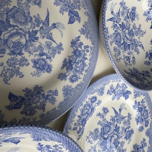 K&ouml;nnte beinhalten: Vier blaue und wei&szlig;e Keramikteller mit einem Blumenmuster und einem Vogeldesign. Die Teller sind kreisf&ouml;rmig angeordnet.