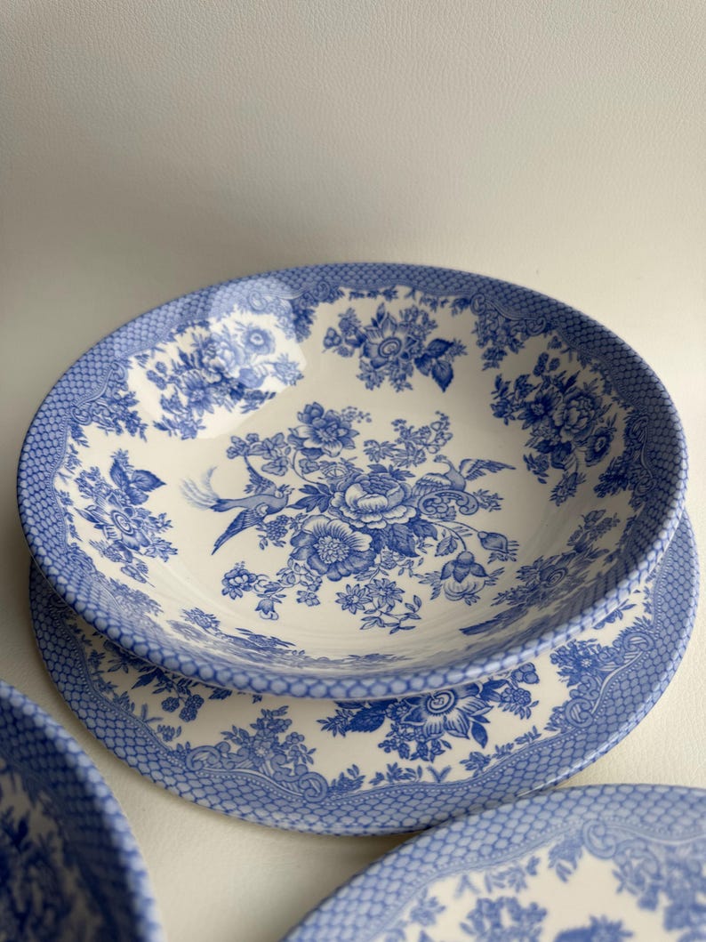 K&ouml;nnte beinhalten: Ein Set aus blauen und wei&szlig;en Keramikschalen mit einem Blumenmuster. Die Schalen haben einen gewellten Rand und ein zartes Blumenmuster.