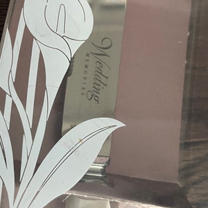May include: A silver cake knife with a white floral design and the words "Wedding Memories" engraved on the blade.