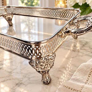 May include: A rectangular silver-toned serving tray featuring an intricate openwork lattice border, two ornate handles with embossed detailing, and four decorative feet shaped like animal paws with detailed fur and claw textures.
