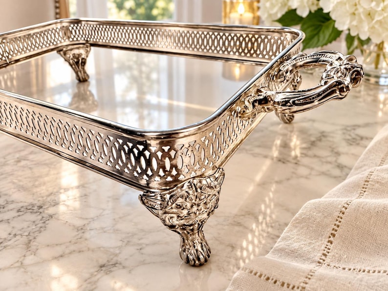 May include: A rectangular silver-toned serving tray featuring an intricate openwork lattice border, two ornate handles with embossed detailing, and four decorative feet shaped like animal paws with detailed fur and claw textures.