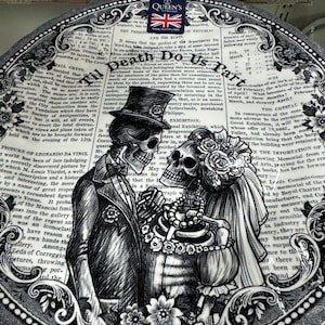K&ouml;nnte beinhalten: Schwarzer und wei&szlig;er Keramik-Dinnerteller mit einem gotischen Design, das zwei Skelette in Hochzeitskleidung zeigt. Der Teller hat einen dekorativen Rand und einen Text&uuml;berlagerung mit den Worten "Til Death Do Us Part".