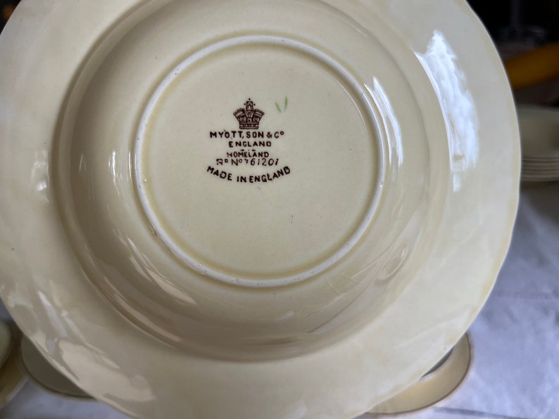 May include: A white ceramic bowl with a brown rim and a brown inscription on the bottom that reads "Myott, Son & Co. England Homeland Reg No 761201 Made in England".