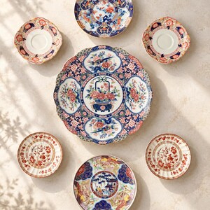 Pu&ograve; includere: Un set di sei piatti e piattini in ceramica con intricati motivi floreali e di uccelli nei toni del blu, rosso e oro. Il set comprende un grande piatto da portata smerlato, due piattini pi&ugrave; piccoli e tre piatti decorativi con bordi dettagliati.