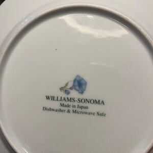 K&ouml;nnte beinhalten: Wei&szlig;e Keramikplatte mit blauem Blumendesign und dem Text "WILLIAMS-SONOMA Made in Japan Dishwasher & Microwave Safe". Die Platte hat eine gl&auml;nzende Oberfl&auml;che.