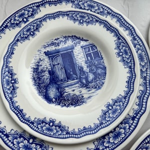 K&ouml;nnte beinhalten: Ein Set aus drei wei&szlig;en Keramiktellern mit einem blauen und wei&szlig;en Blumenmuster. Der mittlere Teller zeigt ein H&auml;uschen mit einer T&uuml;r und zwei Kaninchen davor.