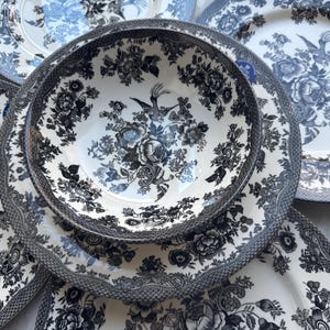 May include: A set of black and white floral patterned dinnerware, including a large bowl, a dinner plate, and a salad plate.