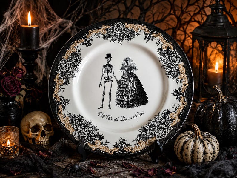 Puede incluir: Un plato redondo de cer&aacute;mica con una ilustraci&oacute;n en blanco y negro de una pareja de esqueletos con ropa de boda. El texto Till Death Do us Part est&aacute; impreso bajo las figuras. El borde tiene un patr&oacute;n floral negro y dorado sobre fondo blanco.