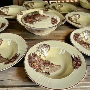 May include: A set of vintage ceramic bowls featuring a woodland scene design. The bowls are cream-coloured with brown and green accents. The design includes trees, a house, and a path.