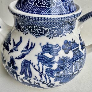 K&ouml;nnte beinhalten: Eine blaue und wei&szlig;e Porzellan-Teekanne mit Deckel, die mit einem traditionellen Weidenmuster verziert ist. Die Teekanne hat einen runden K&ouml;rper und einen Ausguss auf einer Seite. Der Deckel hat einen Knopf oben.