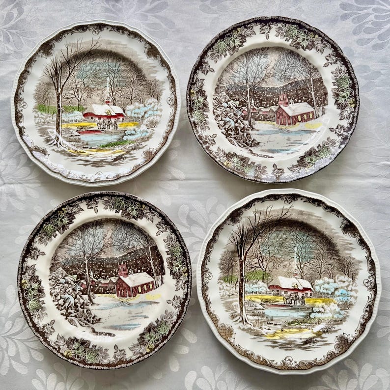 May include: Set of four vintage dinner plates featuring a winter scene with a red farmhouse, snow-covered trees, and a small pond. The plates have a brown and green floral border.
