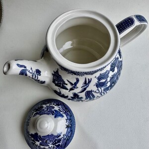 K&ouml;nnte beinhalten: Eine blaue und wei&szlig;e Teekanne mit einem Blumendesign und einem passenden Deckel. Die Teekanne hat einen Henkel und einen Ausguss.