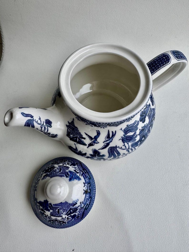 K&ouml;nnte beinhalten: Eine blaue und wei&szlig;e Teekanne mit einem Blumendesign und einem passenden Deckel. Die Teekanne hat einen Henkel und einen Ausguss.